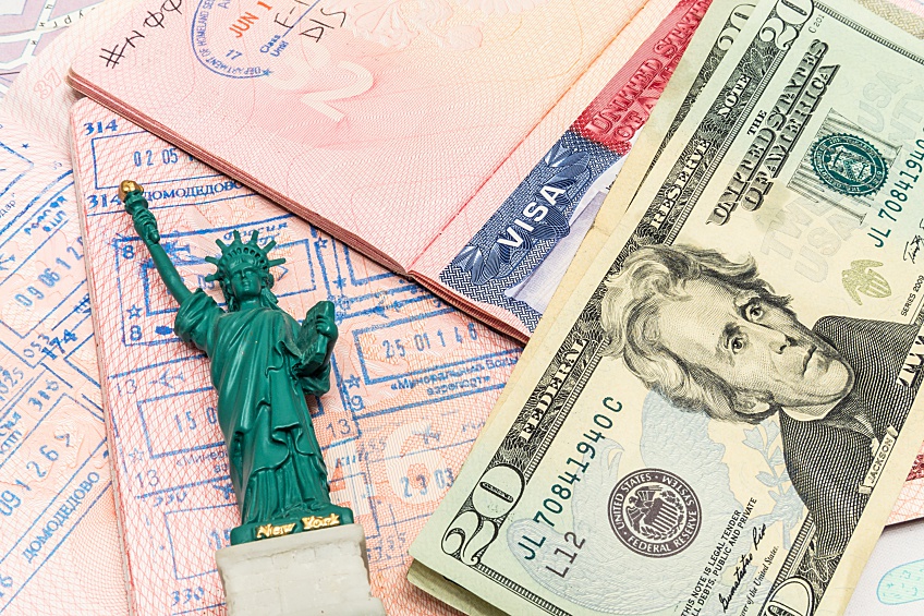 EB-5 visa next to a statue of liberty figurine and a stack of cash representing immigrant investing