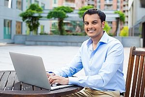 an immigrant businessman on an EB-5 visa who is using his laptop and working outside during the fall