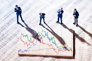 miniature figure overtop an investing-graph