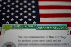 green card in paper USCIS envelope on flag of usa