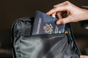 Person sliding passport into a bagpack