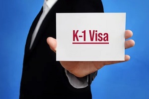 man holding white paper with k1 visa on it