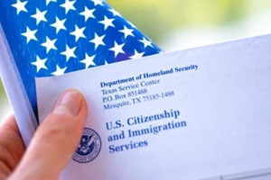 adjustment of status letter from USCIS and flag of USA in hand on green blurred background