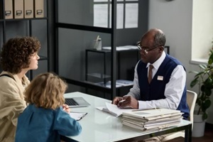 portrait of senior black man consulting mother with child in insurance agency office